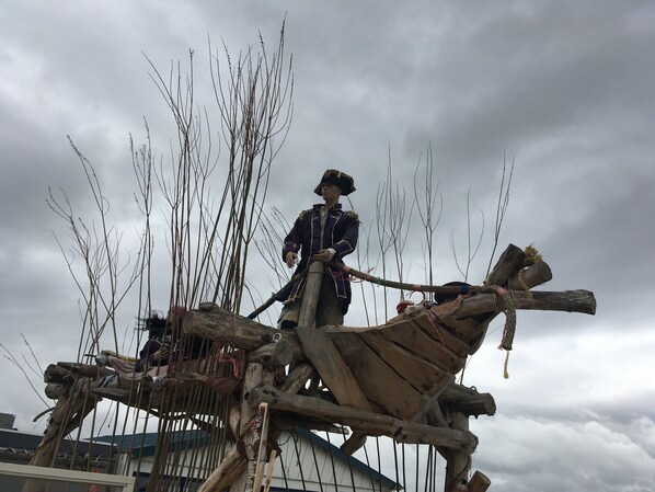 Escena de recreación histórica con una figura vestida con traje de época sobre una estructura de madera.