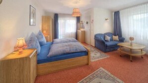 Quarto com cama, sofá, mesa de centro e mesa de cabeceira.