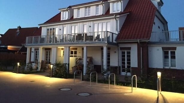 A two-story house with a balcony, a porch, and a garage. - Bright & modern, 4-star apartment for up to 5-6 people (maisonette) (Langeoog)