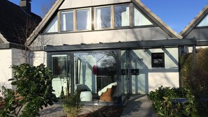 A modern house with a glass entrance, a brick exterior, and a number 178 sign. - Beach and sea(h)r in a vacation home with garden close to the beach at Schilksee⛵️ (KI)