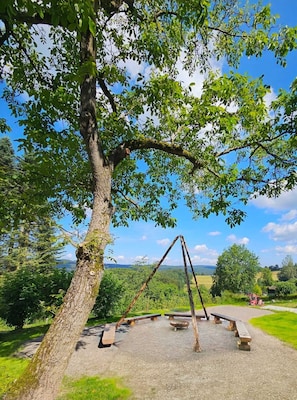 A park with a swing set, picnic tables, and a clear view of the surrounding landscape.