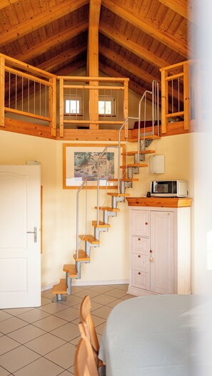 A room with a wooden staircase, a white door, a cabinet, and a bed.