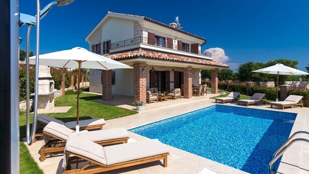 Una casa de dues plantes amb piscina, mobles d'exterior i zona de barbacoa.