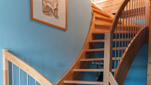 Eine Wendeltreppe aus Holz mit Metallgeländer, ein gerahmtes Bild an der Wand und eine blaue Wand.