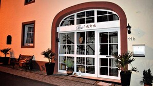 A building with a large arched entrance, a sign reading "Blue", and multiple windows. There are potted plants outside and a bench on the sidewalk. - Take a few days blue, in the holiday home Blue (Berlingen)