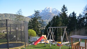 A playground with a trampoline, slide, swing set, and a wooden playhouse. - Vacation apartments Unterluimes (Telfes im Stubai)