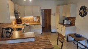 A modern kitchen with wooden countertops, white cabinets, a built-in stove, and a dining area with a table and chairs. - Vacation apartments Unterluimes (Telfes im Stubai)