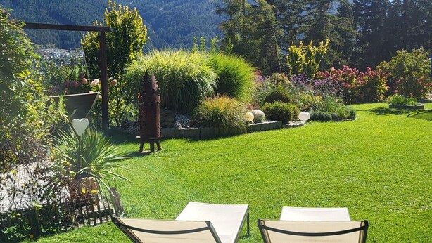 A garden with two lounge chairs, a wooden pergola, and a mountain view. - Vacation apartments Unterluimes (Telfes im Stubai)
