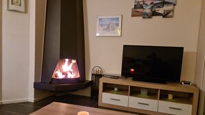 Una sala de estar con chimenea, televisor y una mesa de centro.