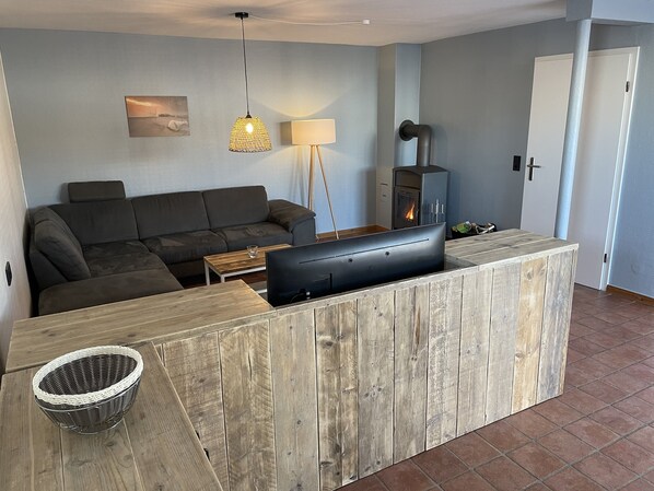 A modern living room with a sofa, a TV, a fireplace, and a wooden accent wall.