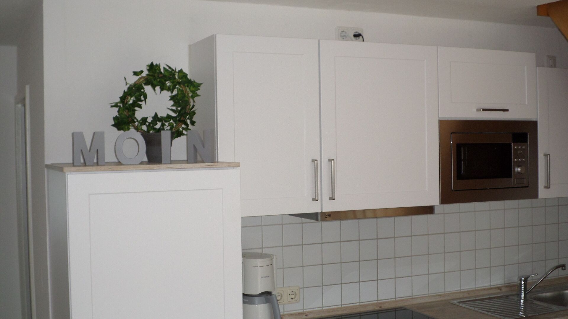 A kitchen with white cabinets, a built-in microwave, and a sink.