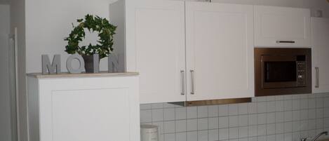 A kitchen with white cabinets, a built-in microwave, and a sink.