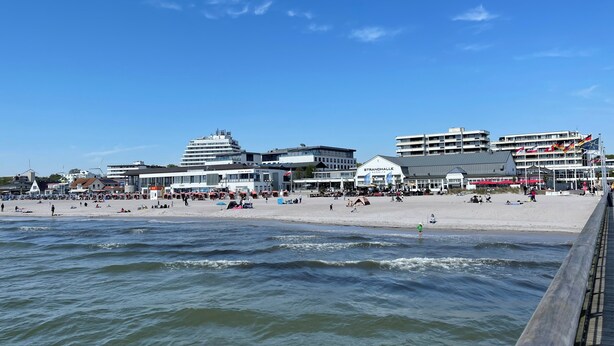 A beachside view with a boardwalk, buildings, and a clear sky. - September 8–21: Off! Cozy vacation rental with a balcony, 2 bedrooms, and a parking space in Grömitz (Grömitz)