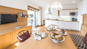 A modern kitchen with white cabinets, a built-in microwave, and a dining area with a wooden table set for a meal.