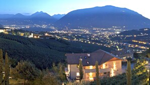 A hillside villa with a view of a town and mountains in the background.