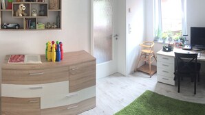 Une pièce comprenant un bureau en bois, une chaise, un téléviseur et une bibliothèque contenant divers objets.