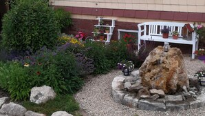 Un jardin agrémenté de diverses plantes et fleurs, un banc blanc et un élément décoratif en roche.