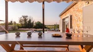Eine Terrasse im Freien mit Esstisch, ein Steinhaus und ein Blick auf die Landschaft.