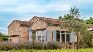 Ein Haus aus Stein mit Ziegeldach, großen Fenstern und Fensterläden.