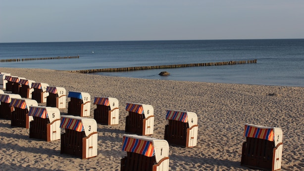 Beach chairs lined up on a sandy beach with a wooden pier in the background. - Sunny, east and south situated comfortable 4-room apartment. (Kühlungsborn)
