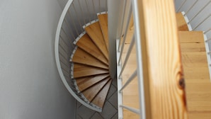 A spiral staircase with wooden steps and white railings. - Sunny, east and south situated comfortable 4-room apartment. (Kühlungsborn)