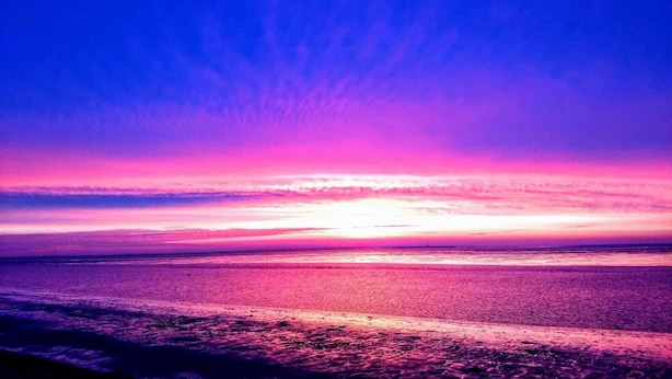 A beach at sunset with a clear sky and calm sea. - Wilhelmshaven Südstrand: Hochw. Duplex apartment right on South Beach (Wilhelmshaven)