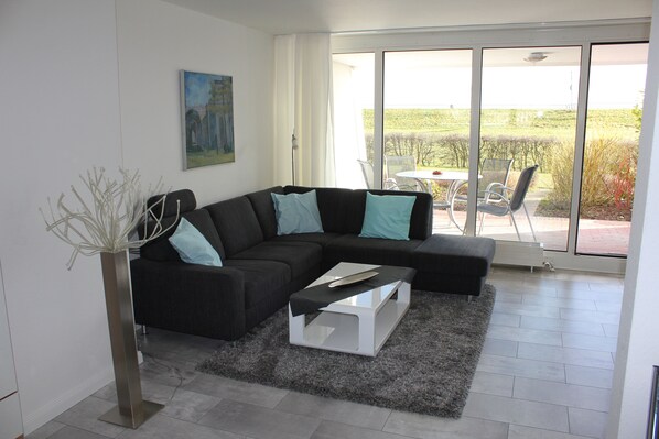A modern living room with a sectional sofa, a coffee table, and a large window offering a view of the outdoors.