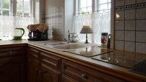 A kitchen with wooden cabinets, a sink, a coffee maker, and a tea kettle.