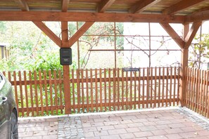 A covered outdoor area with a wooden fence, a brick patio, and a car parked to the left. - Vacation home on the Malerweg with pool, Saxon Switzerland, National Park (Lohmen)