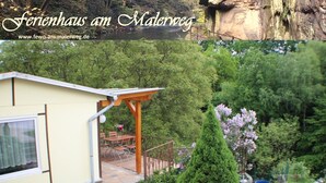 A house with a patio, a small garden, and a view of a forest. - Vacation home on the Malerweg with pool, Saxon Switzerland, National Park (Lohmen)