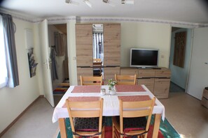 A dining area with a table set for four, a television, and a wardrobe. - Vacation home on the Malerweg with pool, Saxon Switzerland, National Park (Lohmen)