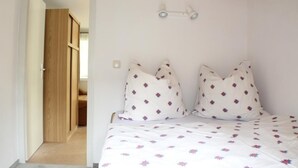 A bedroom with a bed, two pillows, a bedside table, and a wall-mounted light fixture. - Vacation home on the Malerweg with pool, Saxon Switzerland, National Park (Lohmen)
