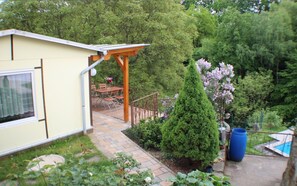Une maison avec un patio, un petit jardin et une vue sur une forêt.