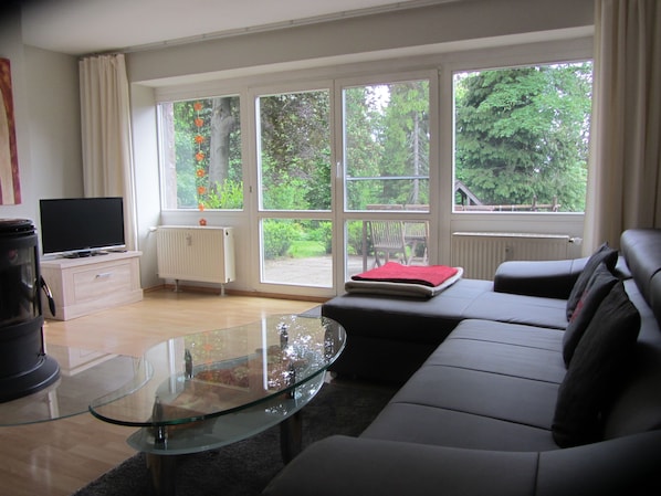 A living room with a glass coffee table, a black sofa, a red book, and a television on a stand. - Holidays in Oberhof -. Thuringia ski No. 1 next to the Rennsteig (Oberhof)