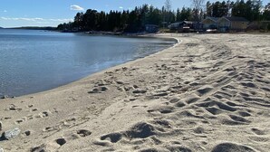 A sandy beach with footprints leading to a calm body of water.