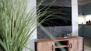 Eine moderne Küche mit integriertem Fernseher, Holzschränken und einer Pflanze im Vordergrund.