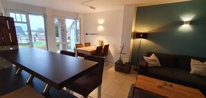 Ein modernes Wohnzimmer mit einem dunklen Holzesstisch, einer Couch und einer Stehlampe.