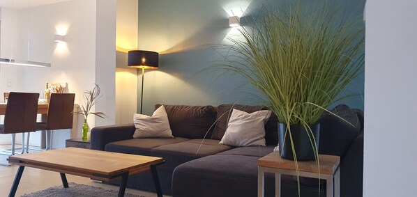 Ein modernes Wohnzimmer mit einem dunkelbraunen Sofa, einem Holztisch und einer Stehlampe.
