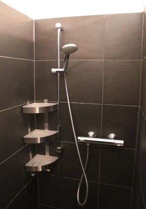 Eine Dusche mit Handbrause und fest installierter Wandarmatur.
