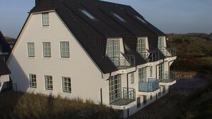 Una casa grande y moderna con varios balcones y ventanas amplias.