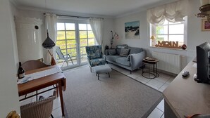 Una sala de estar con sofá, una mesa de comedor y vistas al exterior a través de grandes ventanales.