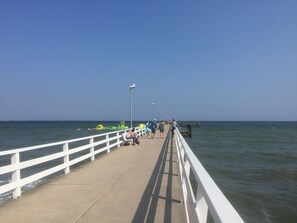 A pier with a white railing, people walking, and a clear sky. - Private residence (Timmendorfer Strand)