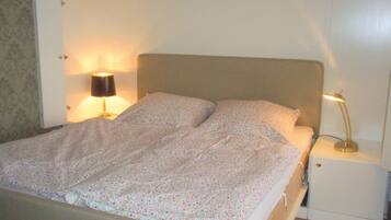 Una cama con ropa de cama floral, una lámpara de noche y una mesita de noche con lámpara.