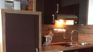 A compact kitchen with dark cabinetry, a wooden countertop, a built-in dishwasher, and a stainless steel sink. - Private residence (Timmendorfer Strand)