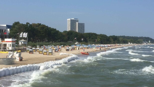 A beach with a row of beach umbrellas and a lifeguard tower. - Private residence (Timmendorfer Strand)