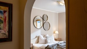 A bedroom with a bed, two bedside tables, a lamp, and three wall-mounted mirrors. - Apartment with seaview, 2 bedrroms. own garden, 5 min. to lake (Tirol)
