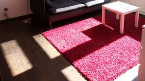 A modern living room with a dark sofa, a white coffee table, and a red rug.