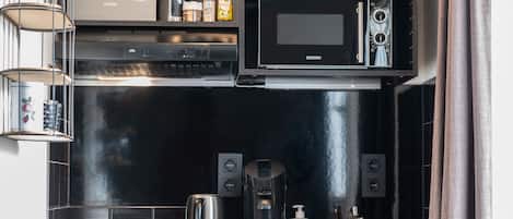 A modern kitchen with a built-in microwave, coffee maker, and kettle.