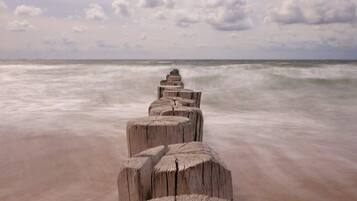 A wooden pathway leading to the ocean with a cloudy sky above.