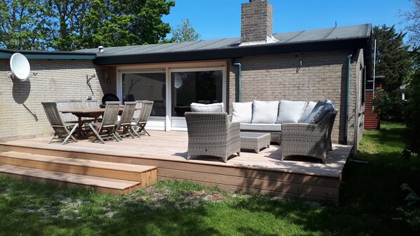 An outdoor patio with wicker furniture, a wooden table, and chairs.